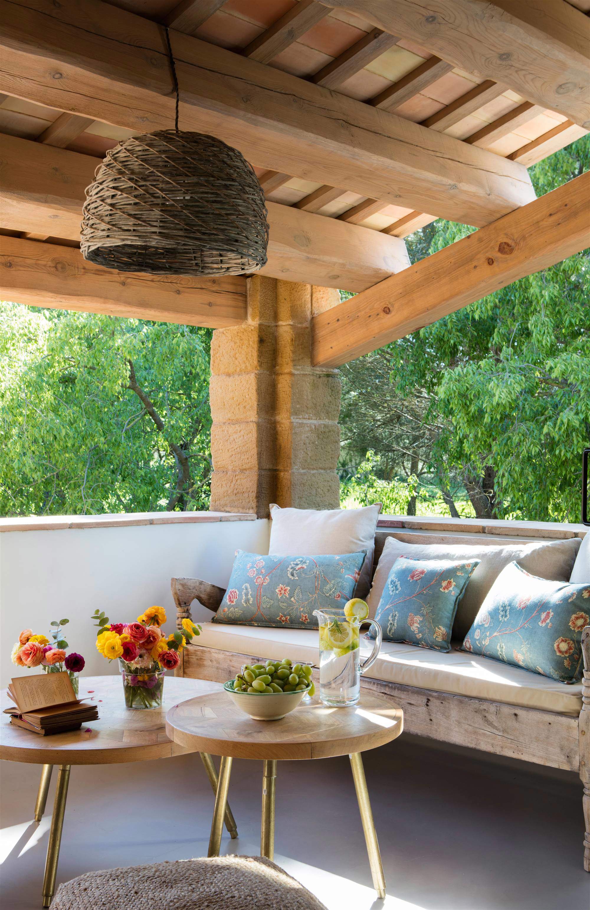 Terraza con sofá de madera, mesas nido y lámpara de fibra.
