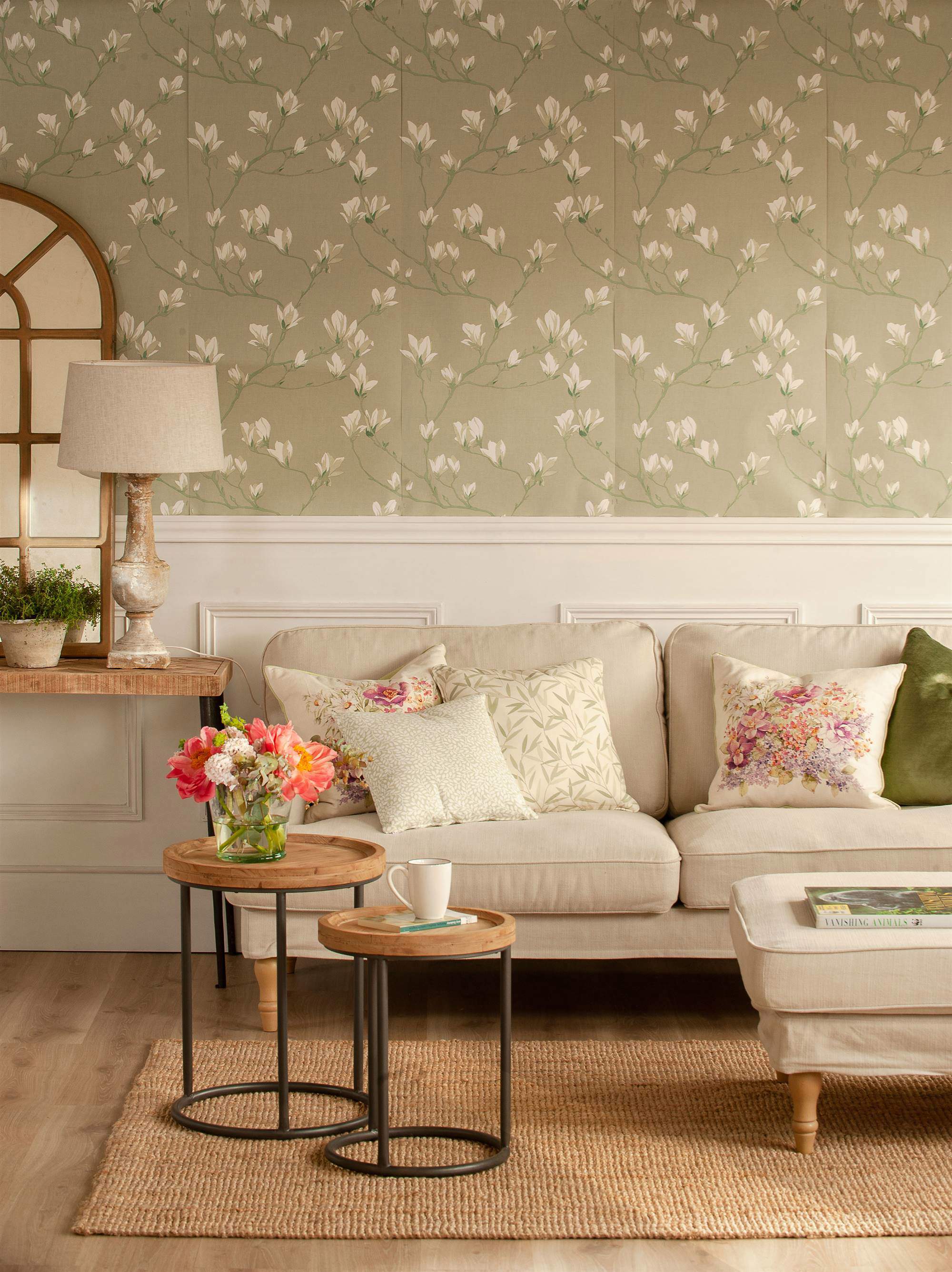 Salón con arrimadero blanco y papel pintado de flores sobre la pared del sofá.