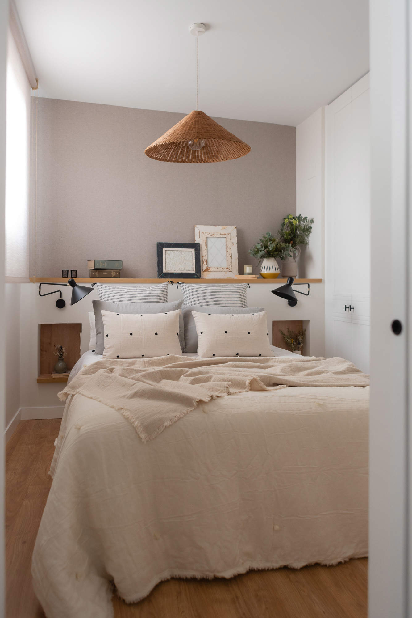 Dormitorio en suite con cabecero a medida, hornacinas de madera y apliques negros por Deco Living