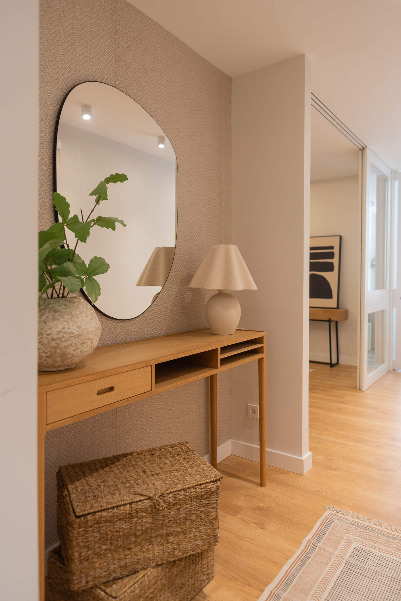 Recibidor con papel pintado, mueble de madera y espejo redondo por Deco Living