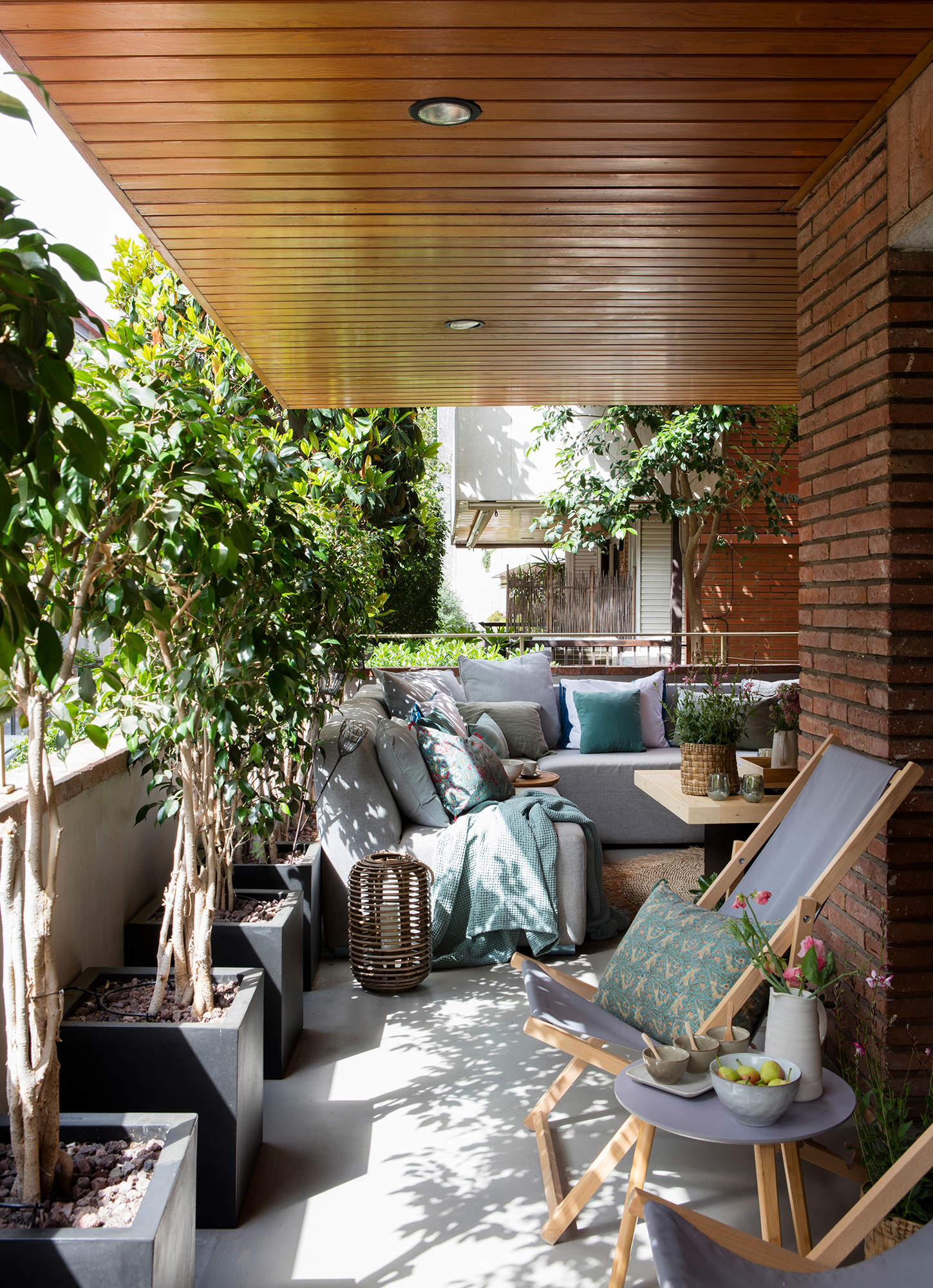 Terraza urbana con sofá rinconero y plantas.