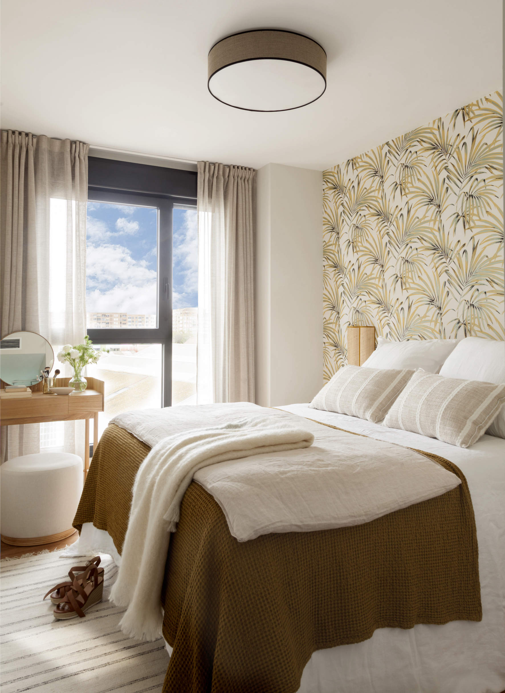 Dormitorio con papel pintado estampado, tocador y ropa de cama blanca y beige Majo Flores