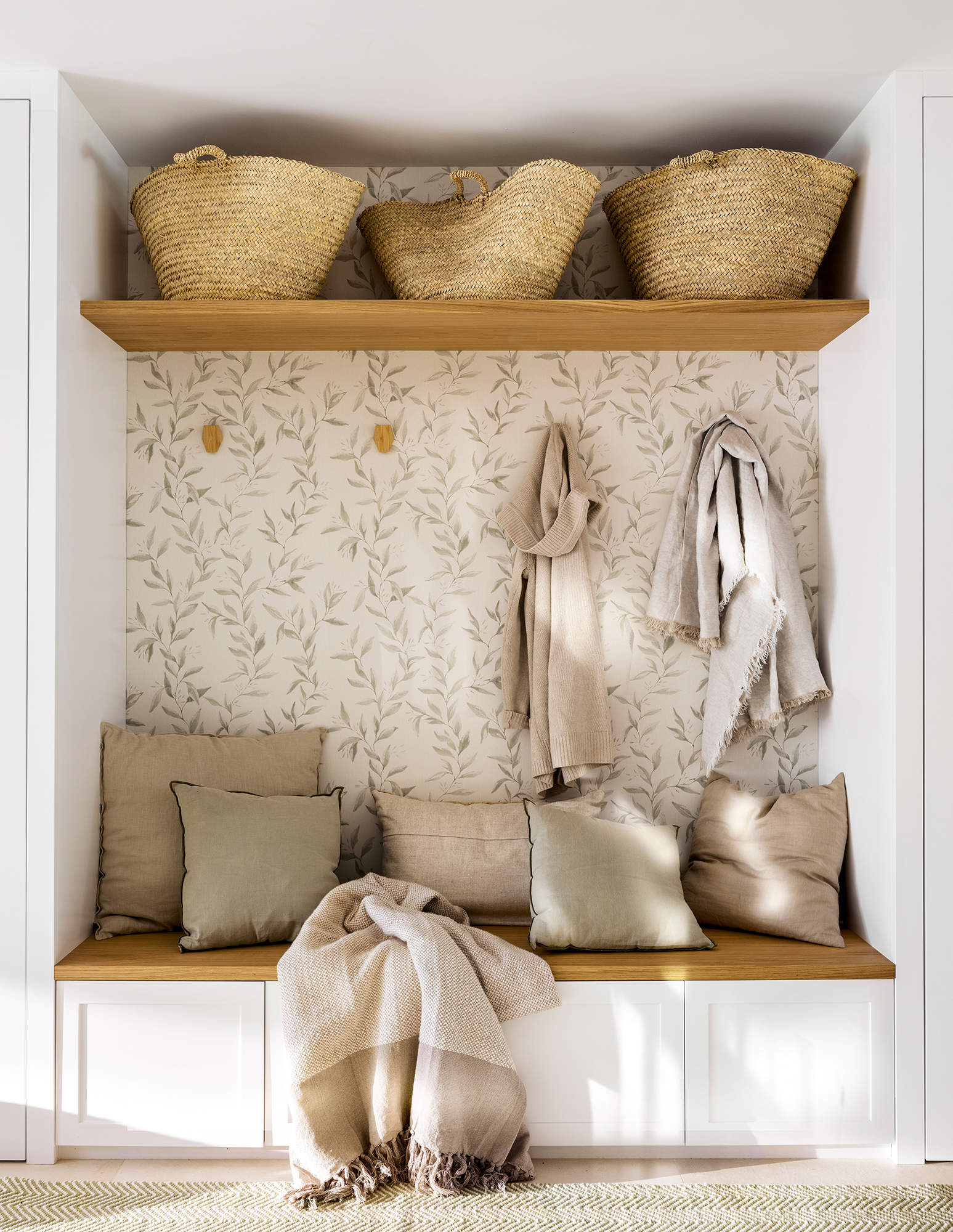 Mueble a medida con percheros para y cestas en un estante. 