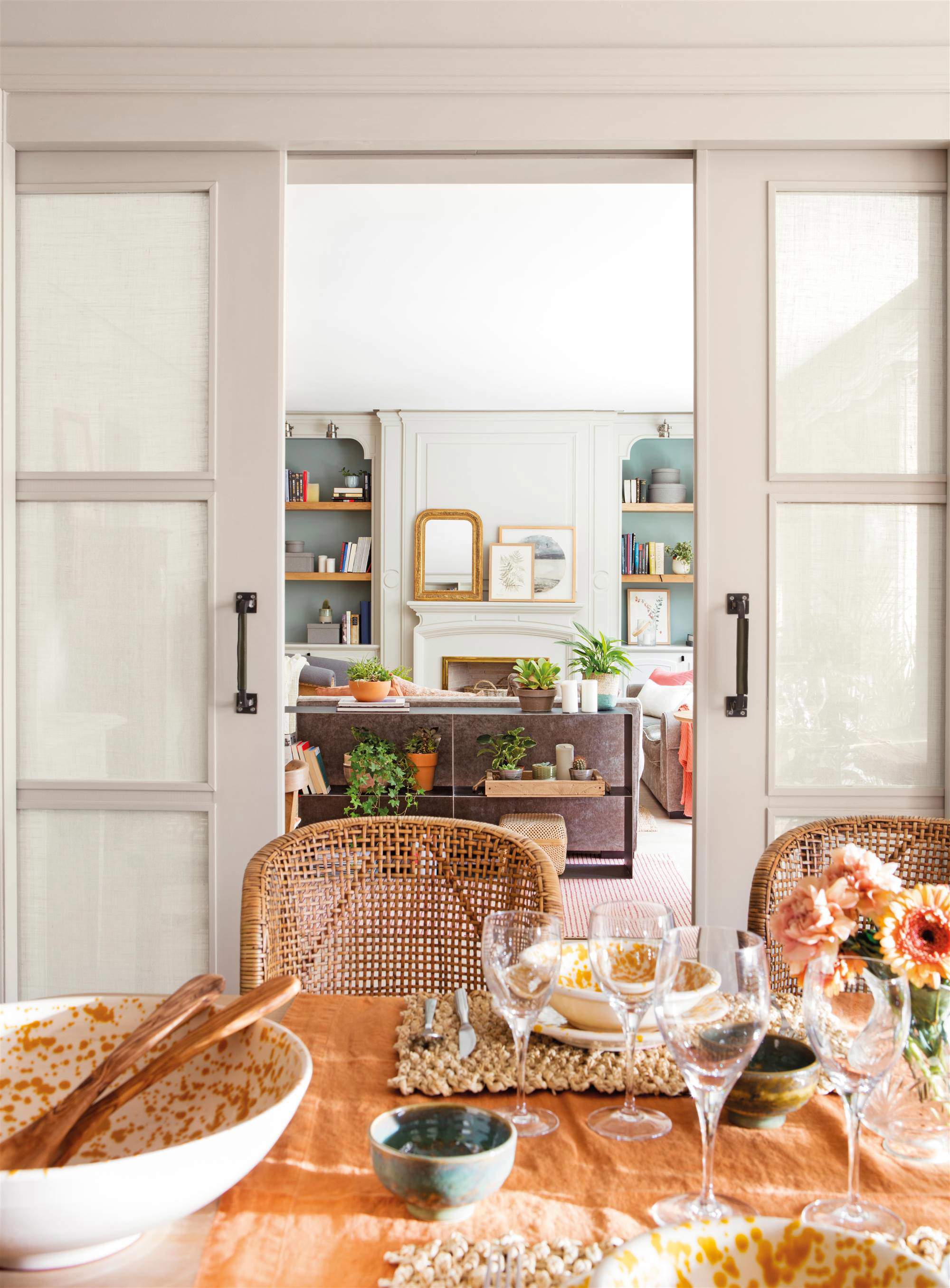 Salón comedor separado por puertas correderas de madera lacada en gris con cuarterones forrados de lino.