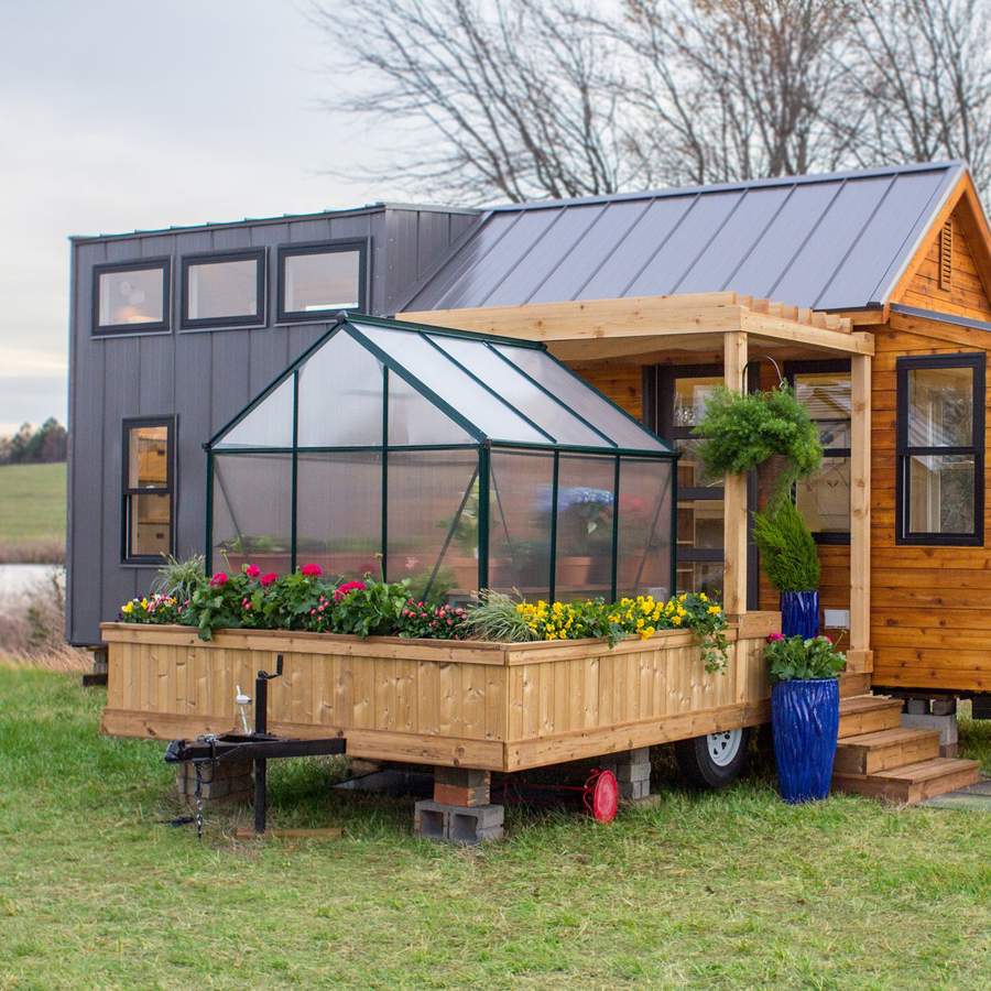 Una mini casa prefabricada de apenas 30 m2 con cocina con barra, un porche  apetecible ¡y hasta invernadero ecológico!