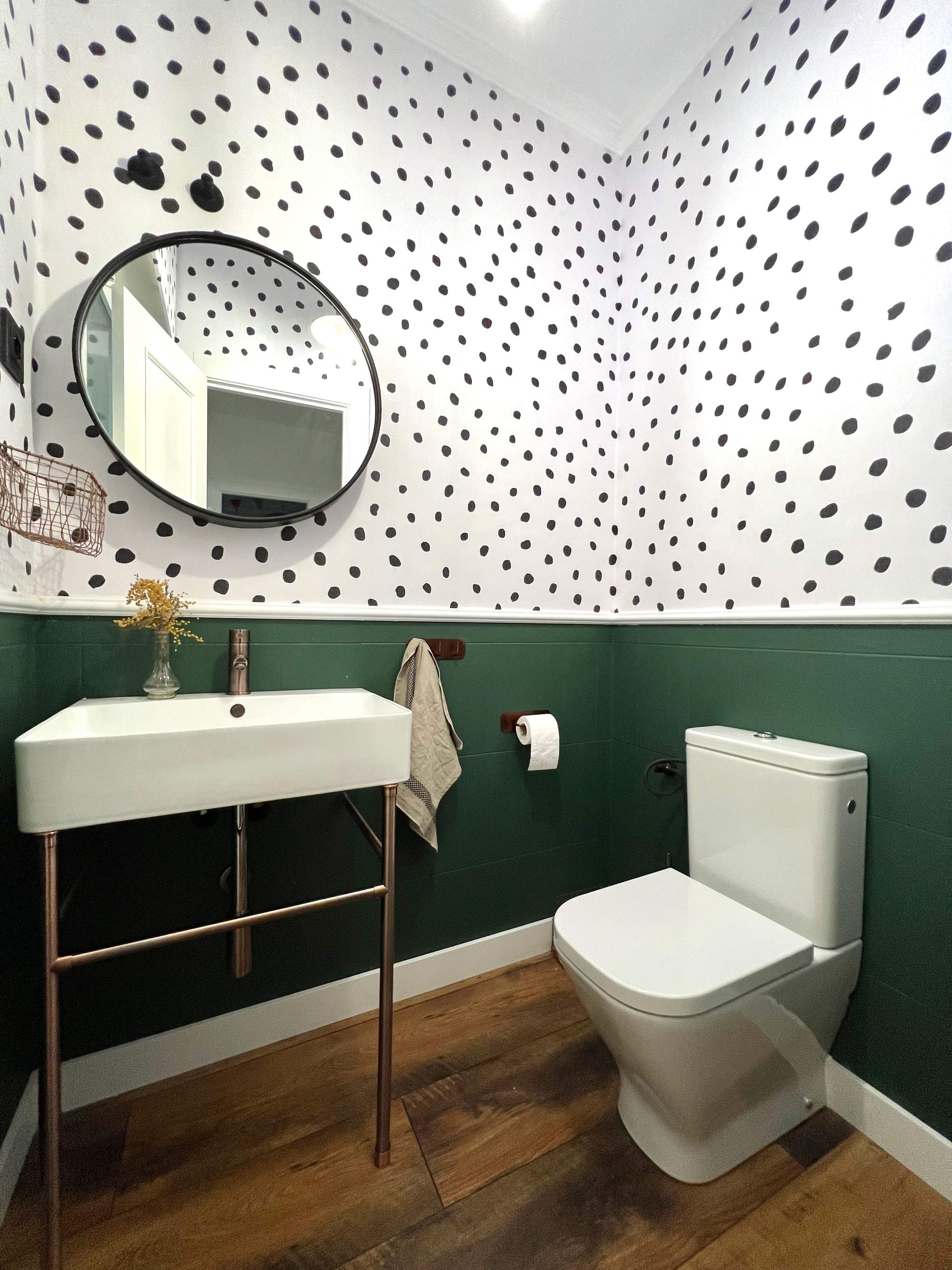 Baño con arrimadero verde y pared con topos. 