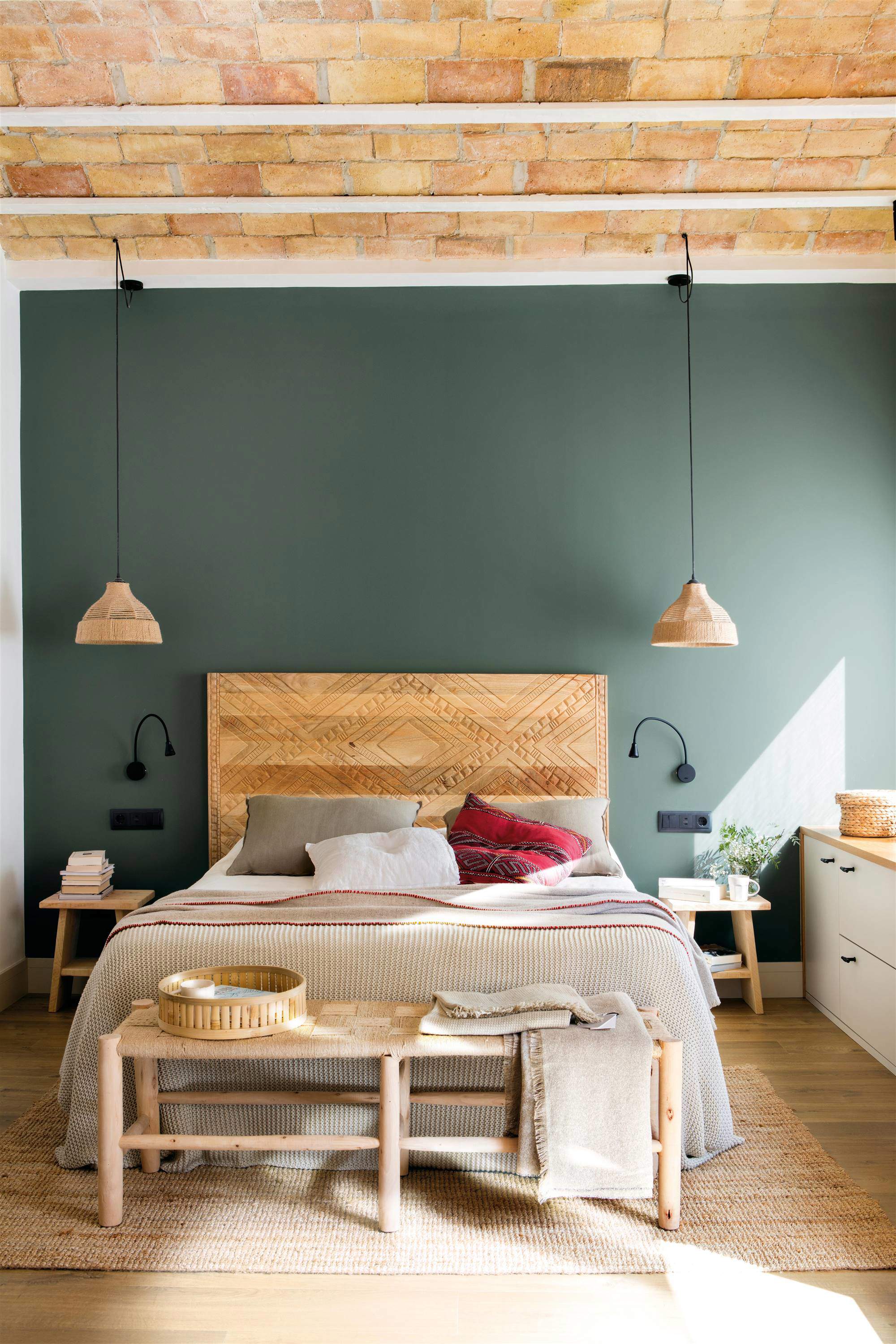 Dormitorio con cabecero de madera y pared pintada en verde.