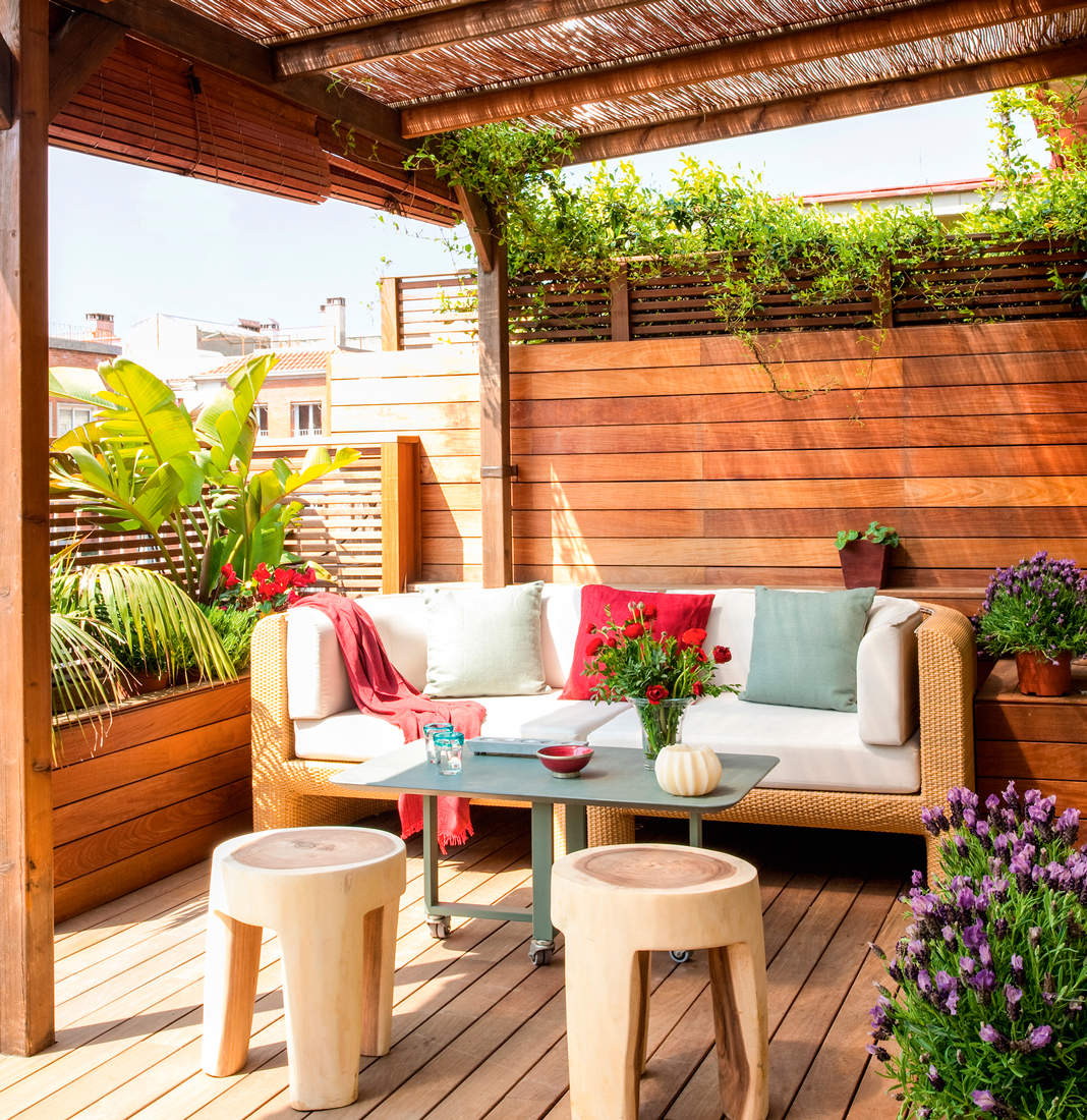 Una terraza con tarima y pared de lamas de madera.