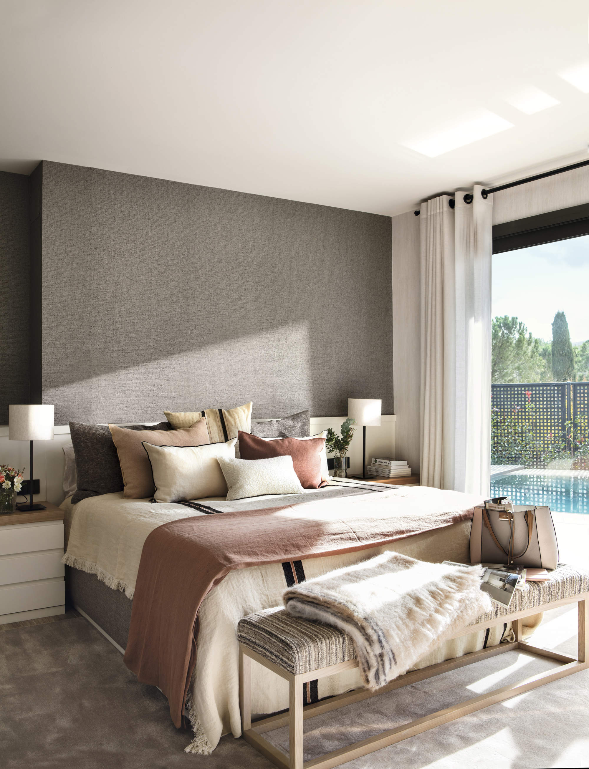 Dormitorio con pared principal en gris, y decoración en tonos neutros y cálidos.