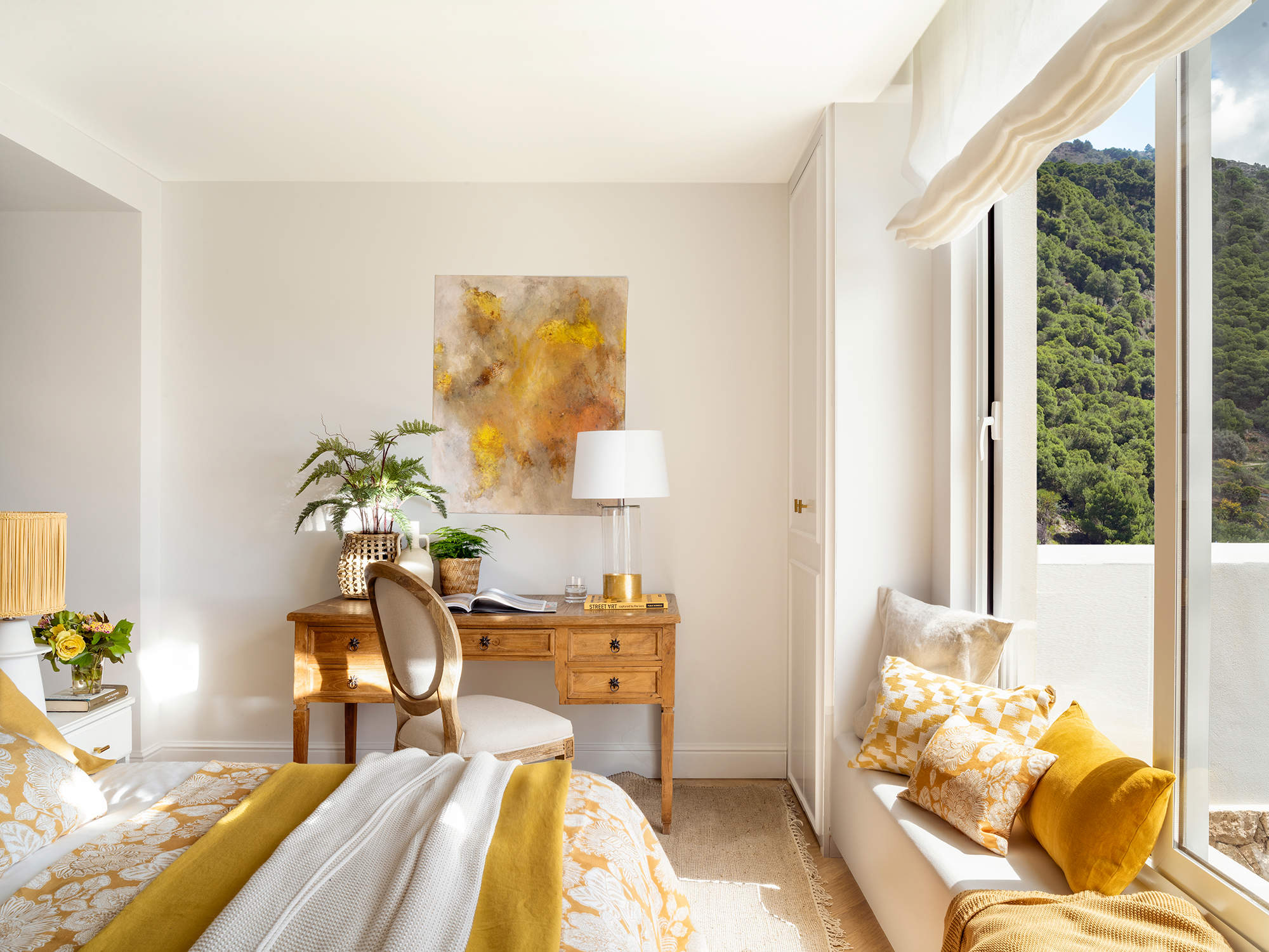 Dormitorio en tonos blancos y amarillos con rincón de trabajo.