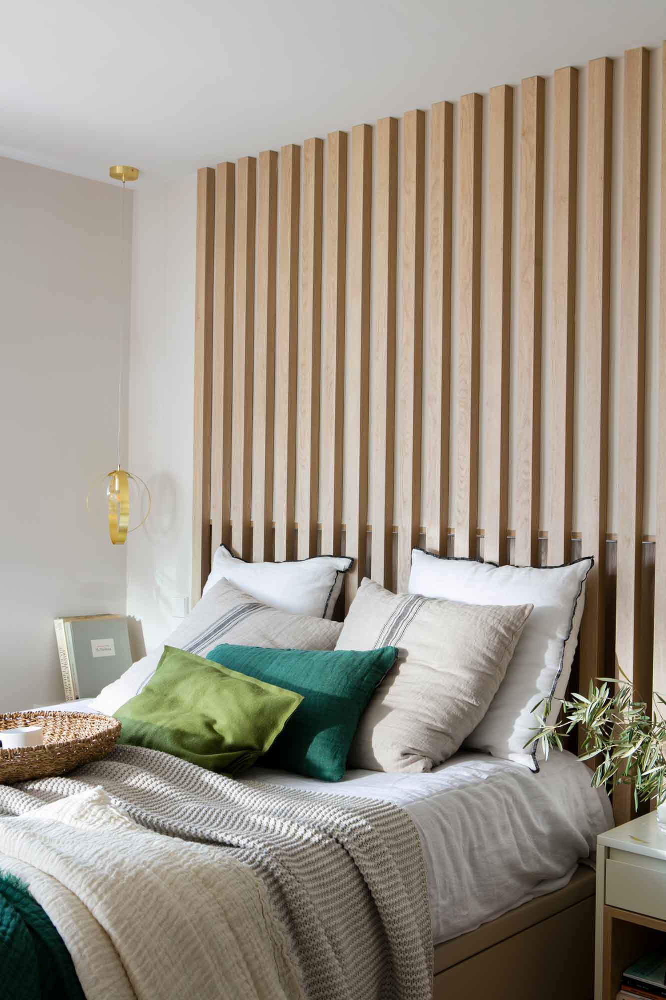Dormitorio con listones de madera en el cabecero.
