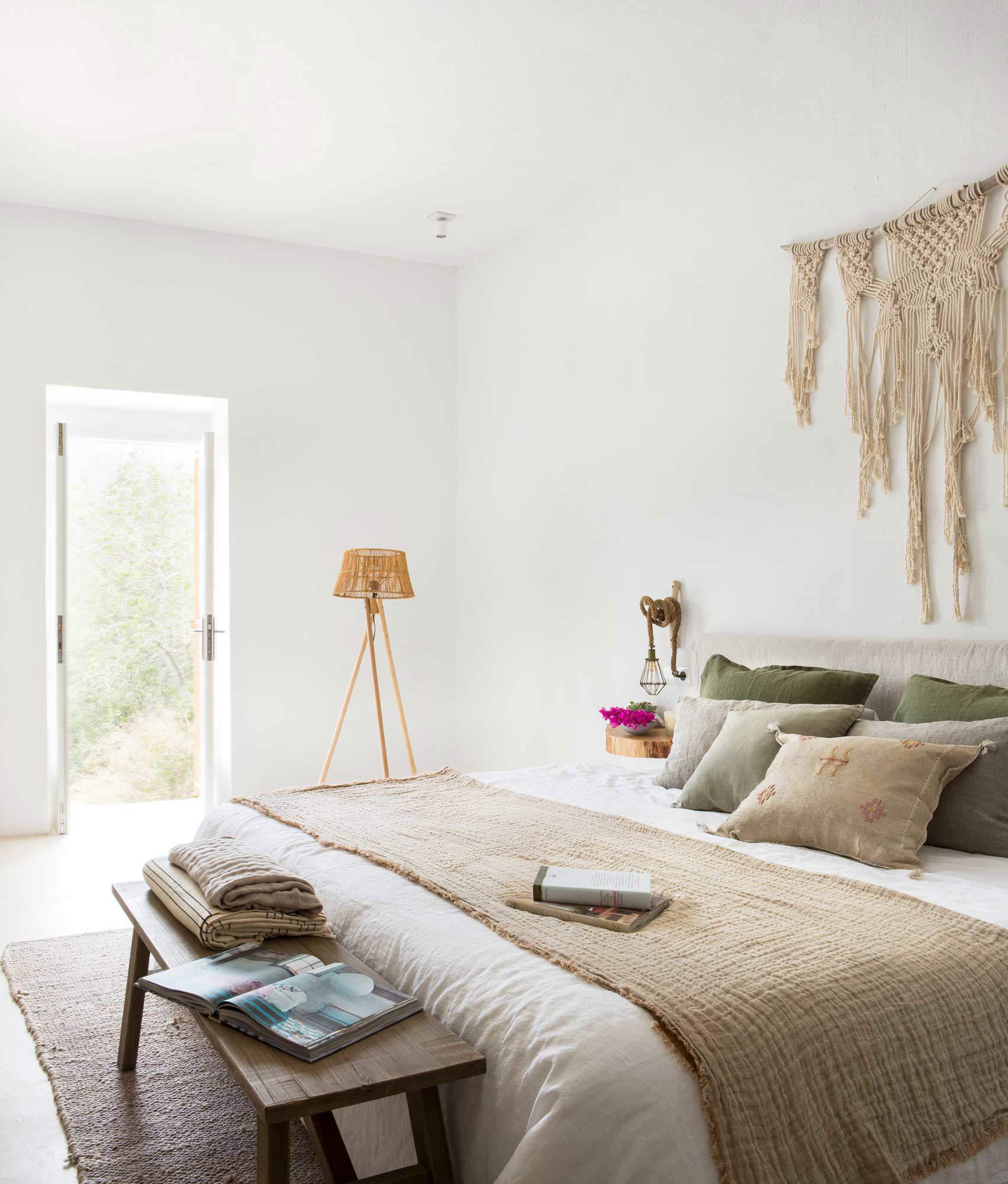 Dormitorio decorado en tonos neutros con cabecero de macramé.