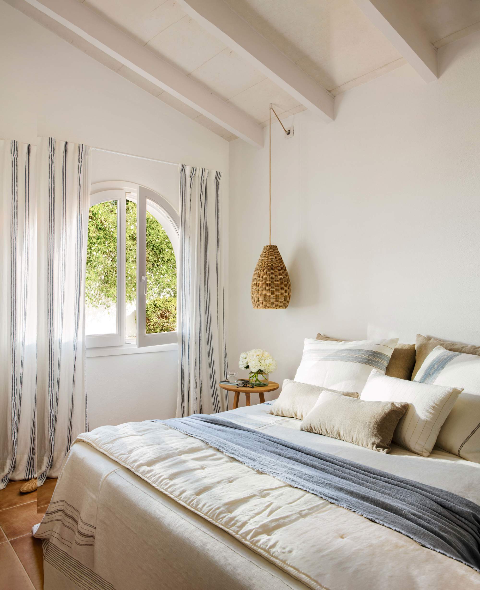 Dormitorio decorado en blanco y azul con lámparas suspendidas.