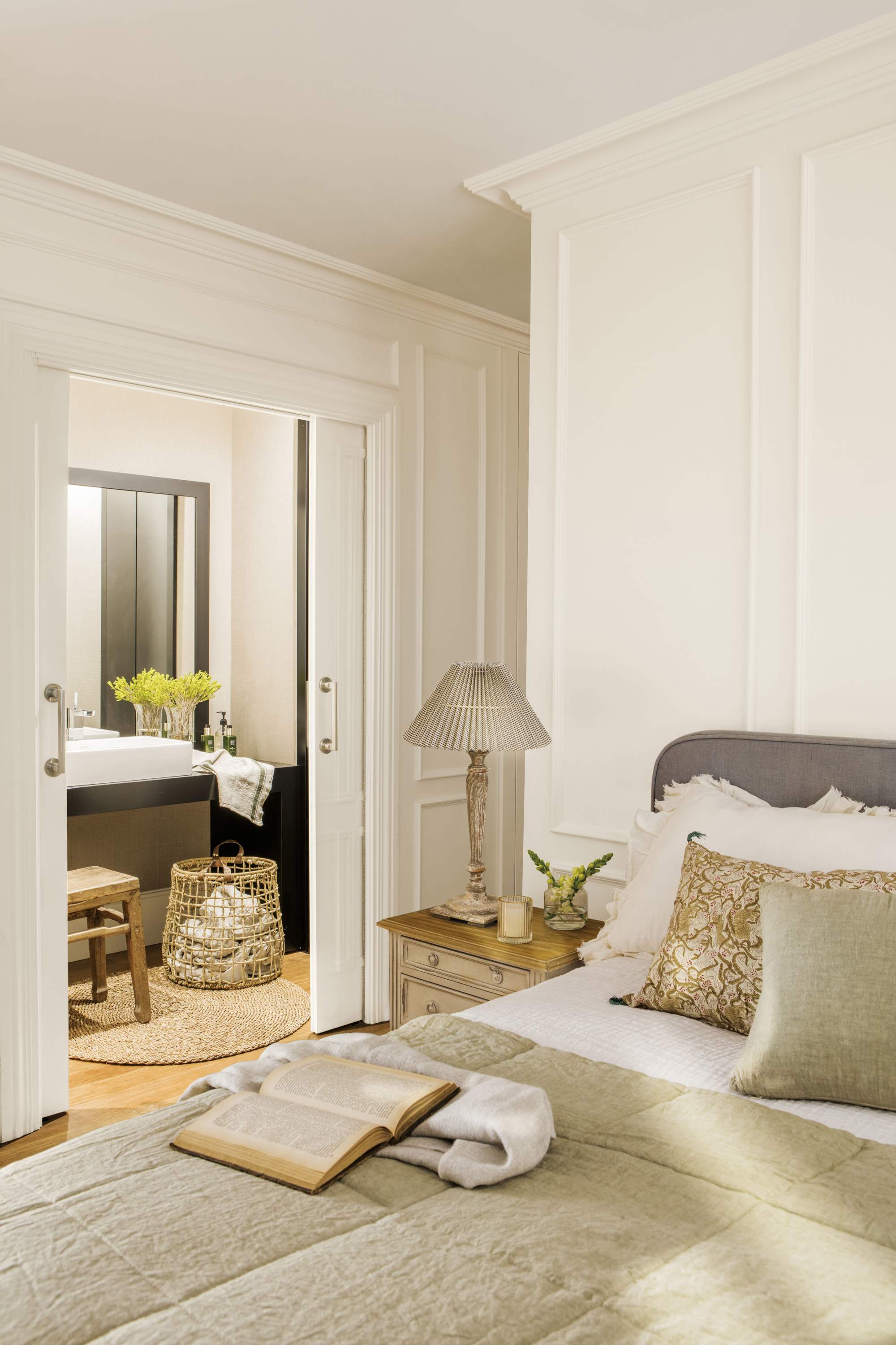 Dormitorio en tonos beige y blanco, con puertas correderas al baño.