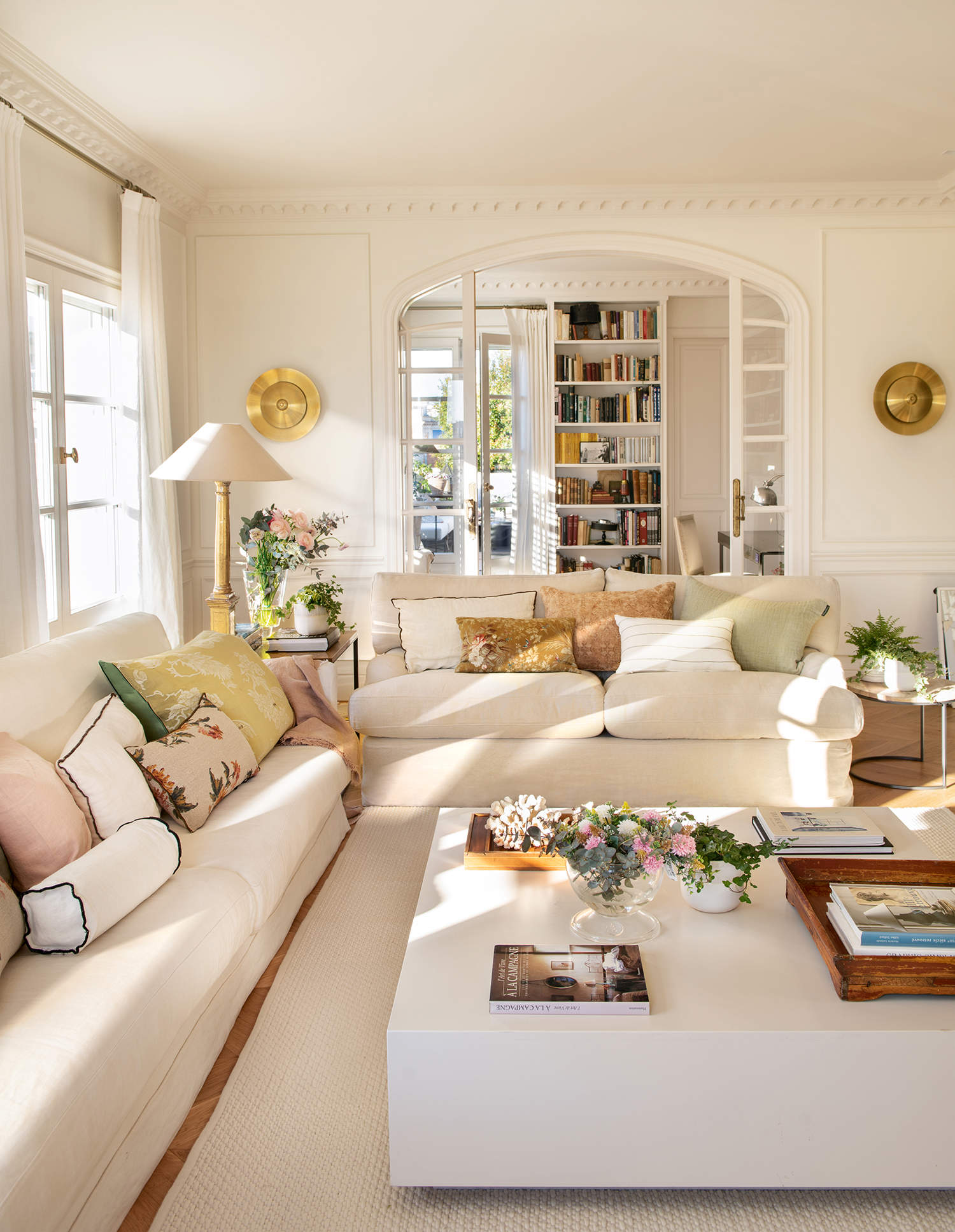 Salón elegante y luminoso con sofás blancos, mesa de centro blanca, cortinas