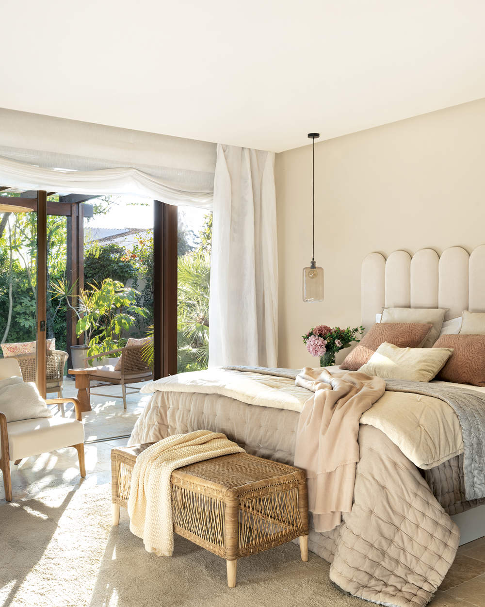dormitorio principal con salida a la terraza, suelo de piedra y alfombra, cabecero tapizado beige y pared color beige, cortina con estor