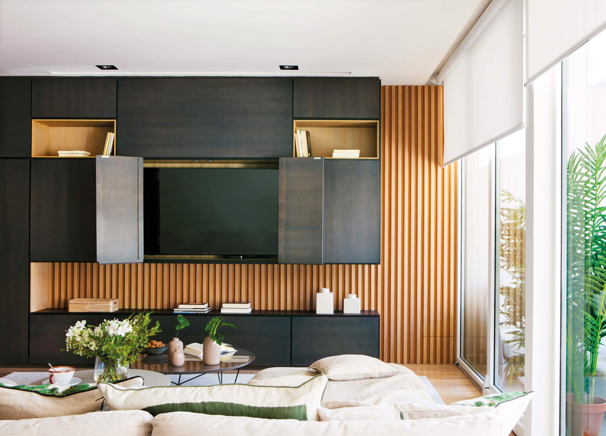 Salón con mueble para televisión en negro y madera con puertas plegables