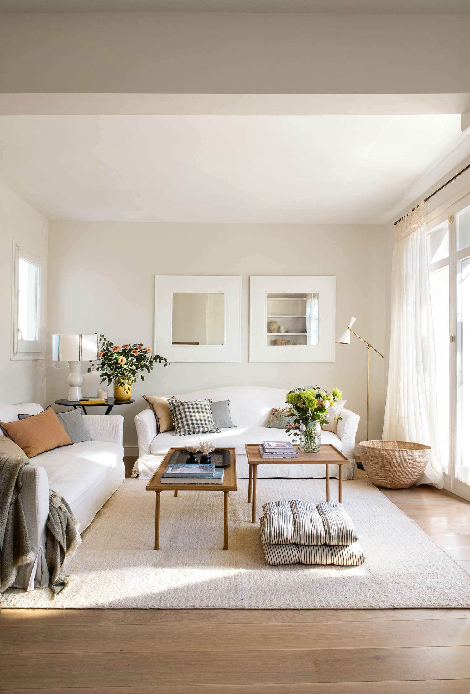 Salón cálido y elegante, sofás blancos y alfombra beige, mesas de centro de madera, suelo de roble