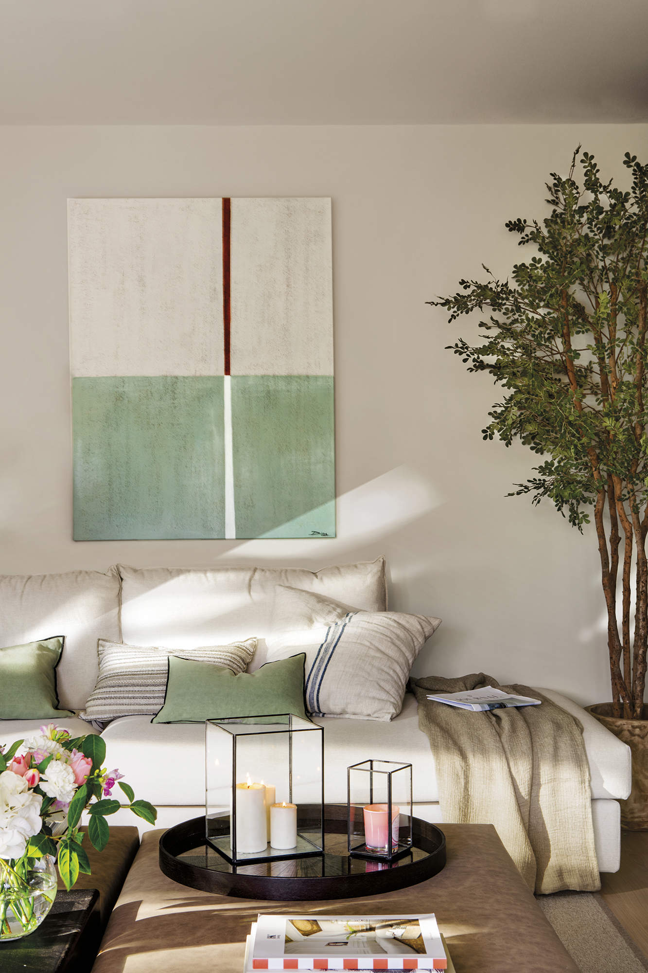 Salo´n con sofa´ blanco, cuadro verde, puf tapizado y olivo por Pia Capdevila