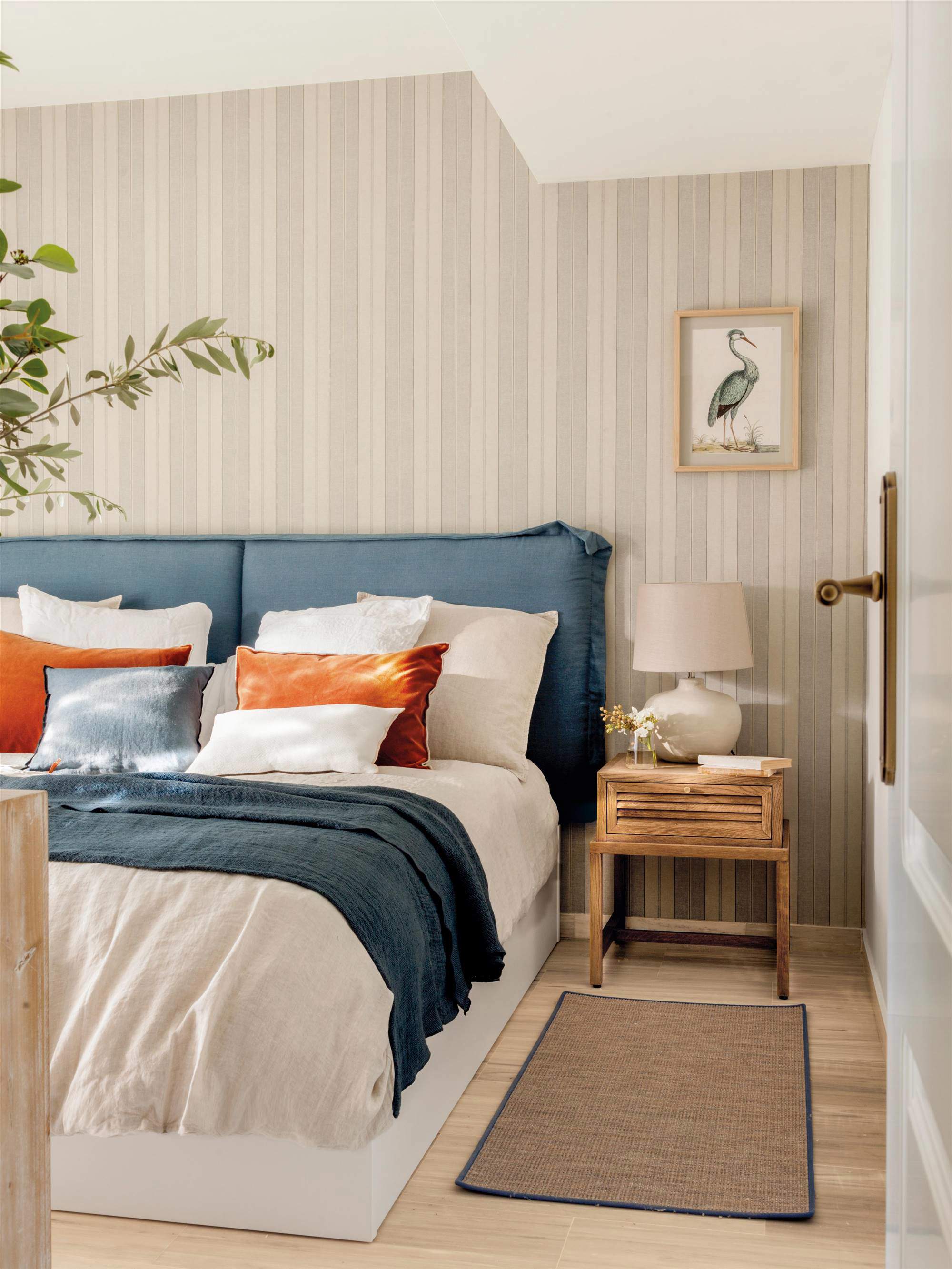 00542267 Dormitorio con cabecero tapizado en azul y papel pintado de rayas