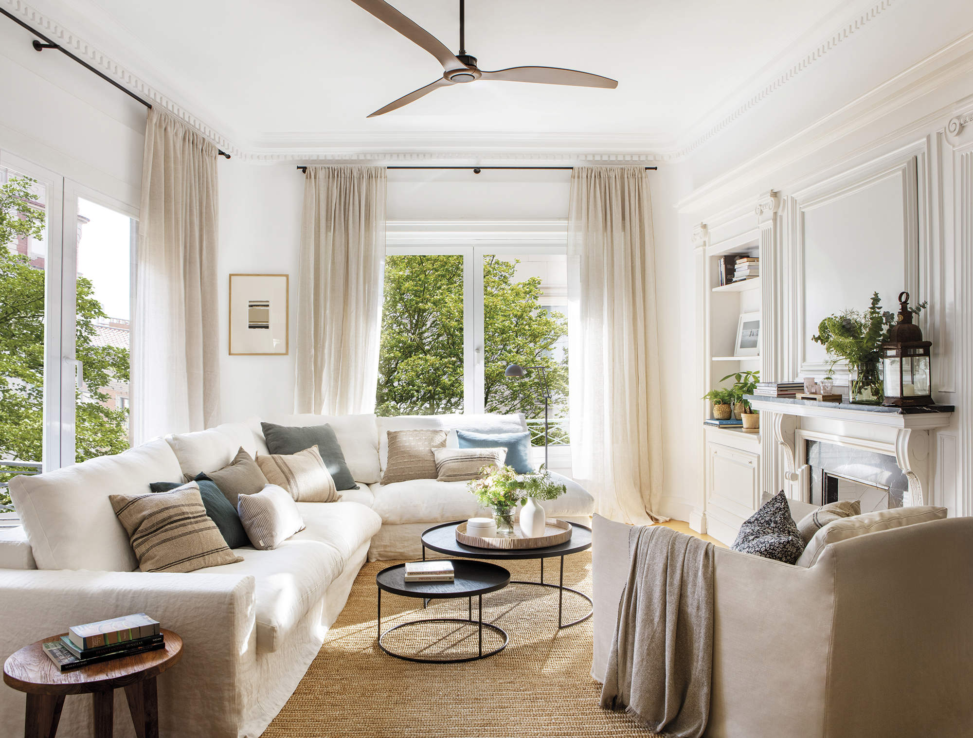 Salón con sofá blanco, alfombra de fibras, butaca beige y molduras