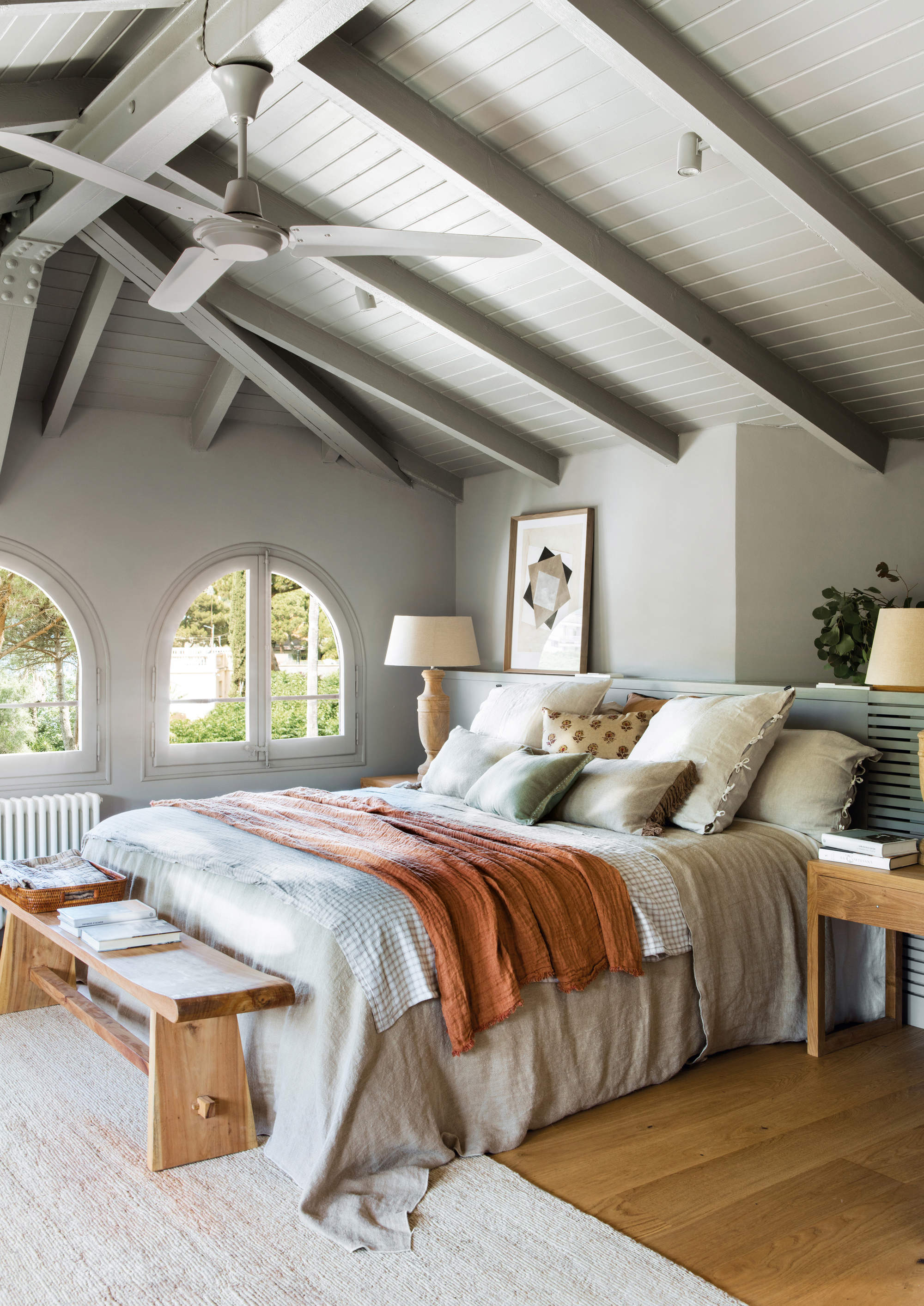 Dormitorio pintado de gris, con ventanas en forma de arco.